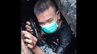 Dalam video yang diunggah terlihat petugas muncul dari dalam got sambil memegang kunci mobil. Got itu airnya hitam. (Foto: Screenshot Video Dok Damkar DKI)