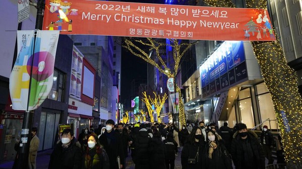 Orang-orang berjalan di sepanjang jalan perbelanjaan pada Malam Natal di Seoul, Korea Selatan, Jumat (24/12/2021).  