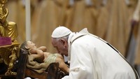 Paus Fransiskus mencium patung bayi Yesus saat misa Natal di Basilita St. Peter, Vatikan, (24/12). (AP Photo/Alessandra Tarantino)