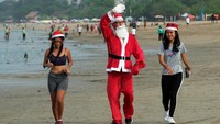 Wisatawan mengenakan busana sinterklas melakukan joging di Pantai Legian. Kegiatan tersebut dalam rangka merayakan Natal 2021. 
