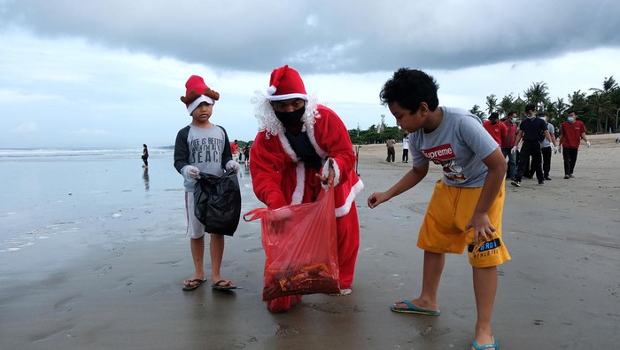 Warga mengenakan busana sinterklas saat membersihkan sampah di Pantai Legian, Badung, Bali, Sabtu (25/12/2021). Kegiatan tersebut dilakukan dalam rangka  merayakan Natal  2021 untuk berbagi kebaikan di kawasan pariwisata itu. ANTARA FOTO/Nyoman Hendra Wibowo/YU