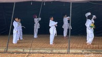 Anak-anak berlatih karate di dalam tenda pengungsian banjir yang berada di kolong Tol Becakayu, Jakarta Timur, Minggu (26/12/2021).