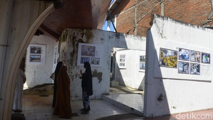 Pengunjung menyaksikan pameran foto bertajuk Tsunami Pandemi di situs tsunami Kapal Atas Rumah, Desa Lampulo, Banda Aceh, Aceh, Sabtu (25/12/2021). Organisasi profesi nirlaba Pewarta Foto Indonesia (PFI) Aceh menggelar pameran foto dengan tema Tsunami Pandemi Siaga Bencana Tangguh Bersama melawan COVID-19 dalam rangka peringatan 17 tahun Tsunami Aceh 26 Desember 2021. ANTARA FOTO/Ampelsa/wsj.