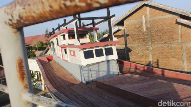 Perahu kayu itu bersandar abadi di atap rumah warga Aceh