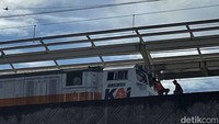 Tampak kereta melintas di saat para pekerja tengah menyelesaikan pembangunan Stasiun Matraman, Jakarta Timur, Minggu (26/12/2021).