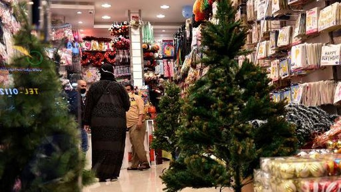 People walk past christmas decorations displayed for sale at a gift shop in Saudi Arabias capital Riyadh on December 7, 2020. - Until barely three years ago, such items were almost impossible to be openly sold in Saudi Arabia, where authorities have clipped the powers of the clerical establishment long notorious for enforcing Islamic traditions. For decades, Christmas sales were largely underground, and Christians from the Philippines, Lebanon and other countries celebrated the festival behind closed doors or in expat enclaves. (Photo by FAYEZ NURELDINE / AFP)