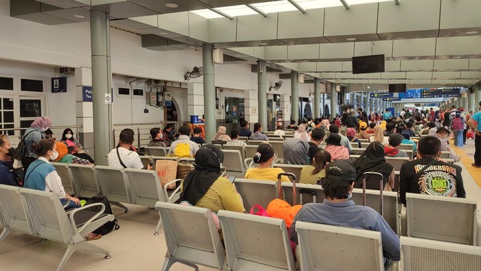 Calon penumpang Stasiun Pasar Senen duduk menunggu kereta datang, Jumat (26/12/2021).
