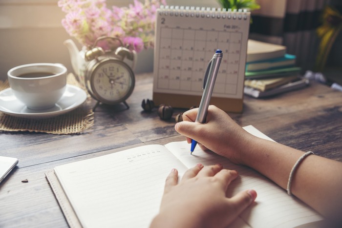 On 2019 Calendar book,Femalehand of planner writing daily appointment.Woman mark and noted schedule(holiday trip) on diary at office desk.Calendar reminder event for planner concept
