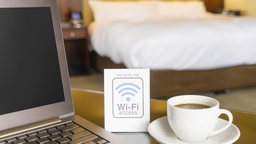 Hotel room with wifi access sign, laptop and cup of coffee