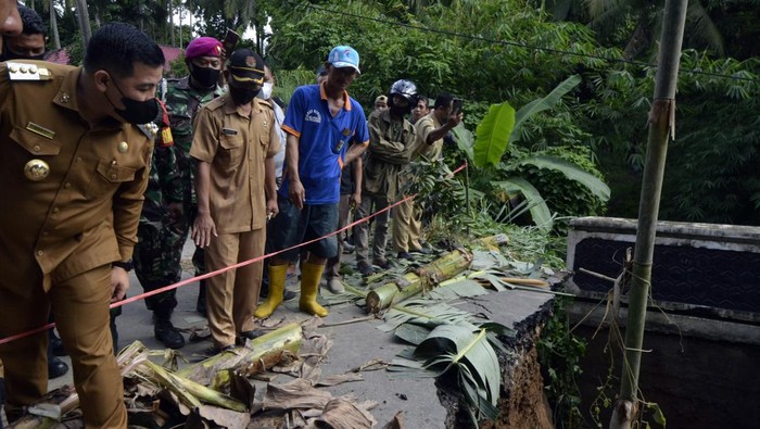 Bupati Pesawaran Dendi Ramadhona (kiri) meninjau kondisi Jembatan Way Gebang yang putus di Desa Gebang, Teluk Pandan, Pesawaran, Lampung, Senin, (27/12/2021). Hujan deras pada Minggu malam (26/12/2021) hingga Senin dini hari menyebabkan Sungai Way Gebang meluap dan mengakibatkan terputusnya jembatan yang menghubungkan Desa Padang Cermin, Batu Menyan, Gebang dan Hanura Pesawaran Lampung. ANTARA FOTO/Ardiansyah/rwa.