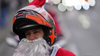 Penampakan salah satu pemotor yang mengenakan kostum Sinterklas saat ikut serta konvoi ke rumah sakit untuk membagikan hadiah Natal kepada para pasien anak di Serbia.
