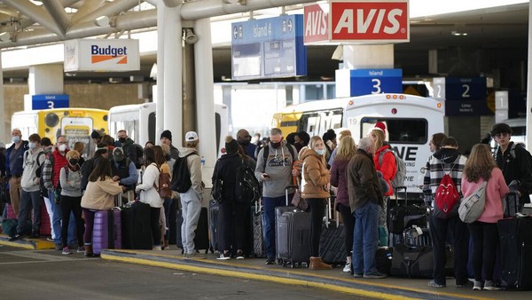 Pelancong mengantri untuk bus antar-jemput ke tempat penyewaan mobil di Bandara Internasional Denver Minggu, (26/12/2021), di Denver. Maskapai membatalkan ratusan penerbangan pada hari Minggu, dengan alasan masalah kepegawaian yang terkait dengan COVID-19 untuk memperpanjang masalah perjalanan negara setelah Natal. AP/David Zalubowski