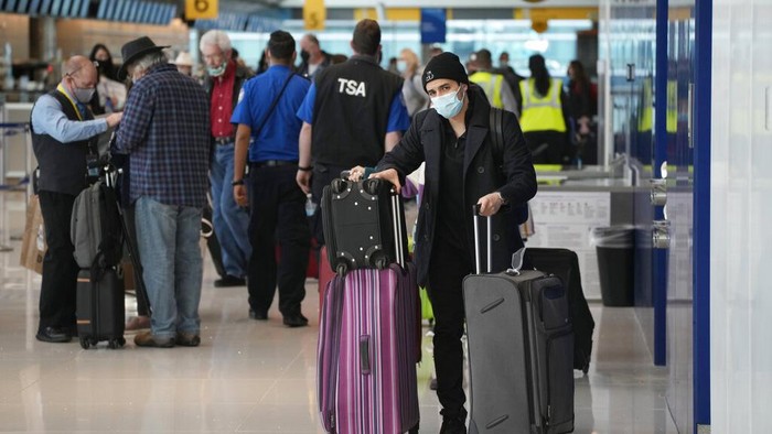 Pelancong mengantri di konter check-in American Airlines di Bandara Internasional Denver, Minggu, 26 Desember 2021, di Denver. Maskapai membatalkan ratusan penerbangan pada hari Minggu, dengan alasan masalah kepegawaian yang terkait dengan COVID-19 untuk memperpanjang masalah perjalanan negara setelah Natal. (Foto AP/David Zalubowski)