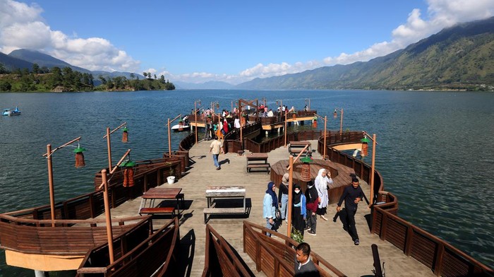 Wisatawan mengunjungi dermaga Pante Menye Danau Laut Tawar pada libur natal dan tahun baru di Kecamatan Bintang, Kabupaten Aceh Tengah, Aceh, Minggu (26/12/2021). Bangunan dermaga yang berbentuk perahu dan bermotifkan kerawang gayo yang menjulur ke arah danau menjadi destinasi bagi wisatawan untuk berswafoto. ANTARA FOTO / Irwansyah Putra/foc.