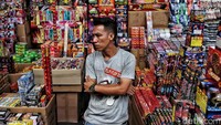 Seorang pedagang menunggu pembeli di depan kiosnya.