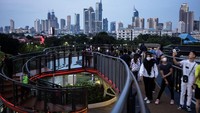 Pengunjung berjalan di Skywalk Senayan Park, Jakarta, Senin (27/12/2021).   
