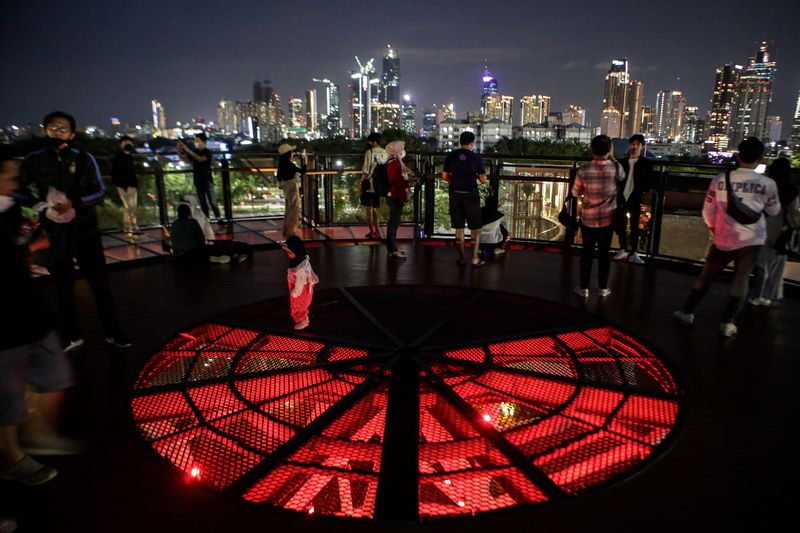 Pengunjung melihat pemandangan dari Skywalk Senayan Park, Jakarta, Senin (27/12/2021). Kawasan tersebut menjadi salah satu objek wisata ibu kota yang ramai dikunjungi oleh warga dengan menyajikan pemandangan lanskap perkotaan. ANTARA FOTO/Fauzan/hp.