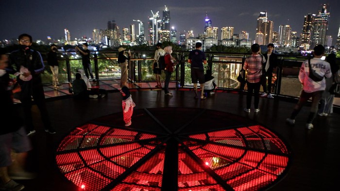 Pengunjung melihat pemandangan dari Skywalk Senayan Park, Jakarta, Senin (27/12/2021). Kawasan tersebut menjadi salah satu objek wisata ibu kota yang ramai dikunjungi oleh warga dengan menyajikan pemandangan lanskap perkotaan. ANTARA FOTO/Fauzan/hp.