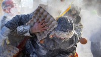 Orang-orang yang bersuka ria mengambil bagian dalam festival Els Enfarinats, di kota Ibi dekat Alicante, Spanyol, Selasa (28/12/2021).  