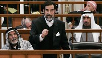 Mantan Presiden Irak, Saddam Huseein saat berbicara di pengadilan sebagai terdakwa di Baghdad, (14/2/2006). Ia divonis mati usai menjalani proses sidang sekitar 4 bulan dengan tuduhan pembantaian 150 orang pada 1985. (Photo by Stefan Zacklin-Pool/Getty Images)