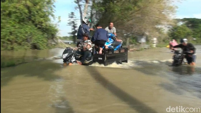 Sungai Bengawan Njero di Lamongan kembali meluap sehingga jalan antarkecamatan terendam hingga satu meter. Ojek motor roda tiga beraksi membantu warga.