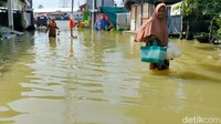 Sejumlah warga beraktivitas di tengah banjir yang merendam kawasan Lamongan, Jawa Timur, Rabu (29/12/2021).