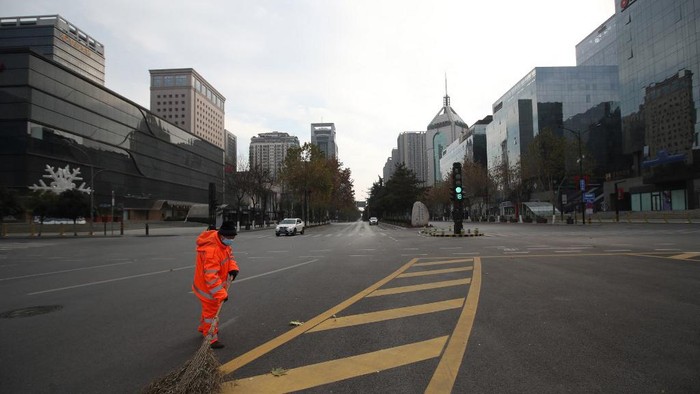 This photo taken on December 28, 2021 shows a sanitation worker sweeping a deserted road in Xian in Chinas northern Shaanxi province, amid a coronavirus lockdown in the city. (Photo by AFP) / China OUT