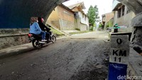 Sebuah patok penanda jarak tampak berada di bawah jembatan penyebrangan perlintasan kereta api. 