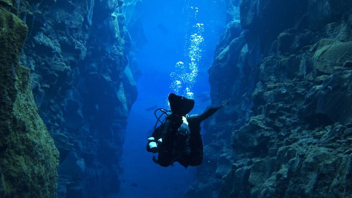 Scuba Diving at Silfra, Iceland in Dry Suits at the Continental Divide at the Þingvellir National Park in Iceland. Glacial runoff water (fresh water). 0 Celsius.