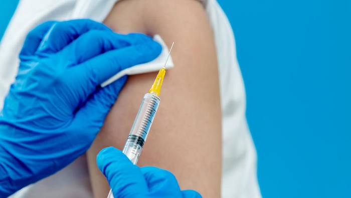 Doctor vaccinating for a boy on blue background.