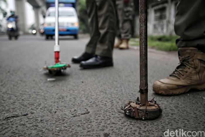 Petugas Satpol PP Kecamatan Cakung  melakukan razia ranjau paku di kawasan Jalan Pulogadung, Jakarta Timur, Kamis (30/12).