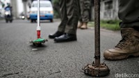 Petugas menyisir jalan raya dengan menggunakan magnet.