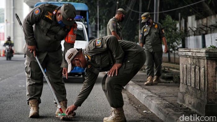 Petugas Satpol PP Kecamatan Cakung  melakukan razia ranjau paku di kawasan Jalan Pulogadung, Jakarta Timur, Kamis (30/12).