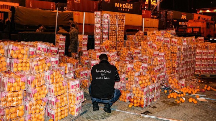 Lebanon Sita Jutaan Narkoba Dalam Jeruk Palsu Lebanon's Interior Minister Bassan al-Mawlawi (L), checks one of the fake oranges filled with Captagon (an illegal drug) pills and dissimulated in boxes containing real fruit, after the shipment was intercepted by the customs and the anti-drug brigade at the Beirut port, in the Lebanese capital, on December 29, 2021. - Lebanese customs agents seized today, nine million Captagon pills hidden in a shipment of oranges in the port of Beirut, destined to one of the Gulf countries, Mawlawi announced. (Photo by ANWAR AMRO / AFP)