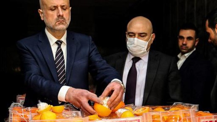 Lebanon Sita Jutaan Narkoba Dalam Jeruk Palsu Lebanon's Interior Minister Bassan al-Mawlawi (L), checks one of the fake oranges filled with Captagon (an illegal drug) pills and dissimulated in boxes containing real fruit, after the shipment was intercepted by the customs and the anti-drug brigade at the Beirut port, in the Lebanese capital, on December 29, 2021. - Lebanese customs agents seized today, nine million Captagon pills hidden in a shipment of oranges in the port of Beirut, destined to one of the Gulf countries, Mawlawi announced. (Photo by ANWAR AMRO / AFP)