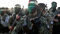 Militan Palestina melukis wajah mereka saat mereka berbaris dengan senjata mereka selama latihan militer.
