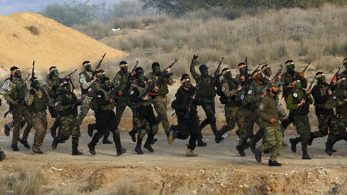 Militan Palestina dengan wajah dicat berbaris dengan senjata mereka dan meneriakkan slogan-slogan selama latihan militer yang diselenggarakan oleh faksi-faksi militer di Rafah, Jalur Gaza selatan, Rabu, 29 Desember 2021. (AP Photo/Adel Hana)