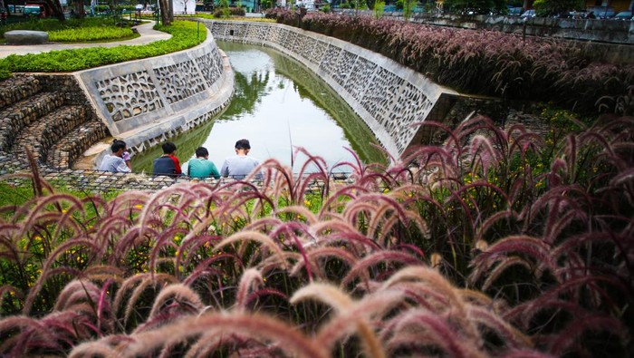 Warga bersantai di Taman Bio Trans, Cempaka Putih, Jakarta, Kamis (30/12/2021). Taman Bio Trans tersebut sebagai bentuk upaya Pemprov DKI  untuk mewujudkan kota ramah lingkungan yang berfungsi menjadi taman terbuka dan sebagai pengendali banjir ketika terjadi peningkatan volume air di saluran sungai. ANTARA FOTO/Rivan Awal Lingga/YU