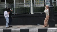 Warga menikmati kawasan Jalan Asia Afrika, Bandung sambil berfoto di trotoar jalan.