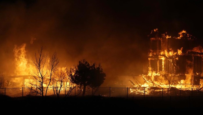 A person stands on a hillside, watching as homes are consumed by wildfires Thursday, Dec. 30, 2021, in Superior, Colo. (AP Photo/David Zalubowski)