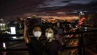 Warga berswa foto dengan latar belakang suasana matahari terbenam di Skywalk Senayan Park, Jakarta, Jumat (31/12/2021). Sejumlah warga memilih menikmati senja terakhir 2021 di lokasi yang menyuguhkan lanskap Ibu Kota tersebut. ANTARA FOTO/Sigid Kurniawan