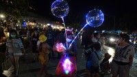 Pedagang menawarkan dagangannya kepada warga dan wisatawan yang mengisi malam tahun baru di kawasan Kuta, Badung, Bali, Jumat (31/12/2021). Warga dan wisatawan memadati sejumlah titik jalanan di kawasan Kuta meskipun tidak ada penyelenggaraan pesta perayaan pergantian tahun untuk mencegah penyebaran pandemi COVID-19. ANTARA FOTO/Fikri Yusuf