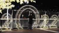 Seorang pengunjung yang mengenakan masker berpose untuk foto di depan dekorasi yang diterangi lampu pada Malam Tahun Baru di Seoul, Korea Selatan, Jumat, (31/12/2021). AP/Lee Jin-man