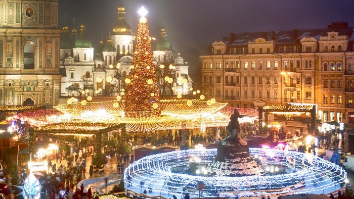 Crowds of people celebrate the New Year around the Christmas tree with the St. Sofia Cathedral in the background in Kyiv, Ukraine, Friday, Dec. 31, 2021. Despite of COVID-19 quarantine restrictions, a lot of Ukrainians enjoy outdoor New Year events, often ignoring protective measures. (AP Photo/Efrem Lukatsky)