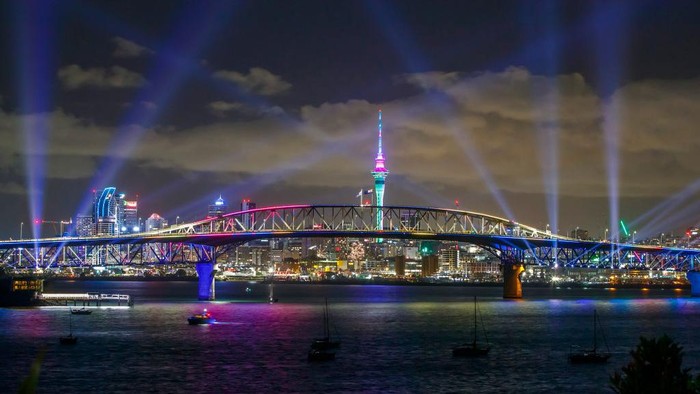 Semarak Perayaan Tahun Baru 2022 di Sejumlah Negara Dunia AUCKLAND, SELANDIA BARU - 01 JANUARI: Pertunjukan cahaya dari Skytower dan jembatan pelabuhan selama perayaan Malam Tahun Baru Auckland pada 01 Januari 2022 di Auckland, Selandia Baru. Pertunjukan cahaya bernama 'Auckland Is Calling' menggantikan kembang api biasa karena pembatasan COVID-19 pemerintah tetapi menandakan sambutan bagi pengunjung dari Selandia Baru dan akhirnya dunia ke wilayah tersebut. (Foto oleh Dave Rowland/Getty Images untuk Auckland Unlimited)