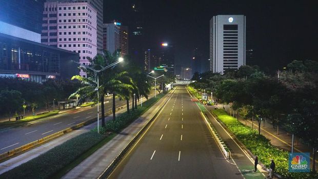 Suasana kawasan Sudirman - Thamrin saat pemberlakuan crowd free night (CFN) Seorang pedang kopi keliling melewati ruas jalan utama di kawasan jalan Sudirman-Thamrin, Jakarta, Sabtu (1/1/2022). Sejak pukul 22.00 WIB terpantau kendaraan dan warga sangat lengang. Kendaraan operasional polisi tampak menyusuri ruas-ruas jalan yang menjadi titik penutupan jalan.Malam pergantian tahun 2021 menuju 2022 di pusat Kota Jakarta berlangsung sepi. Pemerintah Provinsi DKI Jakarta bersama Polda Metro Jaya menutup 11 ruas jalan sejak pukul 22.00 WIB.Dari pantauan dilokasi sejumlah ruas jalan di Jakarta terpantau lengang. Tak banyak kendaraan melintas. Kendaraan operasional polisi tampak menyusuri ruas-ruas jalan yang menjadi titik penutupan jalan (CNBC Indonesia/ Tri Susilo)