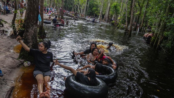 Sejumlah wisatawan bermain air di kawasan pemandian air gambut Danum Bahandang Tangkiling di Palangkaraya, Kalimantan Tengah, Minggu (2/1/2022).  