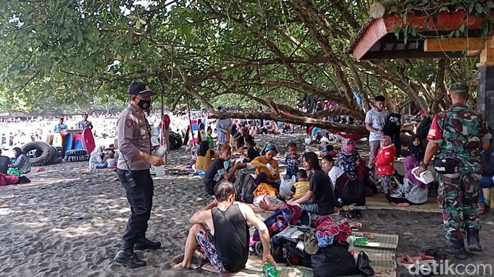 Polisi membagikan masker ke wisatawan yang memadati Pantai Batukaras Pangandaran