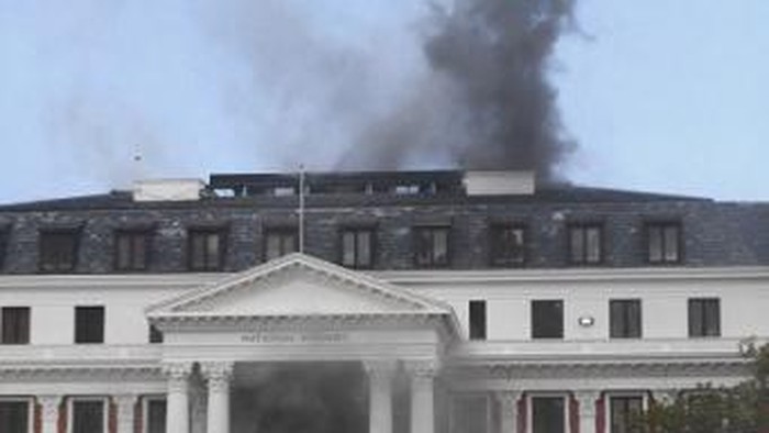 Smoke billows from the roof of a building at the South African Parliament precinct in Cape Town on January 2, 2022, during a fire incident. - A major fire broke out in the South African parliament building in Cape Town on January 2, 2022.
Firefighters were present at the building as large flames and a huge column of smoke were seen at around 0530 GMT. (Photo by RODGER BOSCH / AFP)