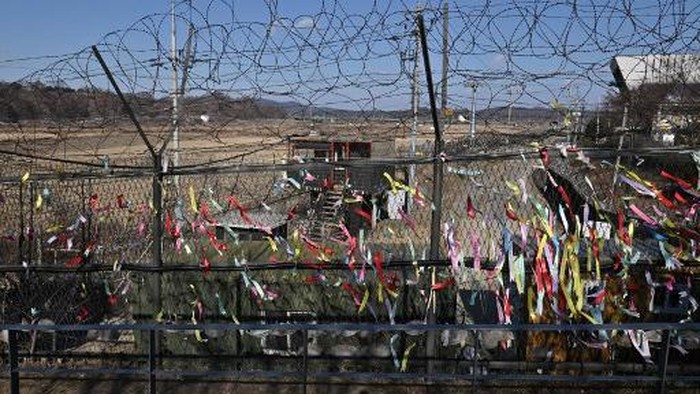 A South Korean guard post is seen through a military fence decorated with ribbons wishing for peace and reunification of the Korean Peninsula at Imjingak peace park near the Demilitarized zone (DMZ) dividing the two Koreas in Paju on December 17, 2021, on the tenth anniversary of the death of North Korean leader Kim Jong Il. (Photo by Jung Yeon-je / AFP)